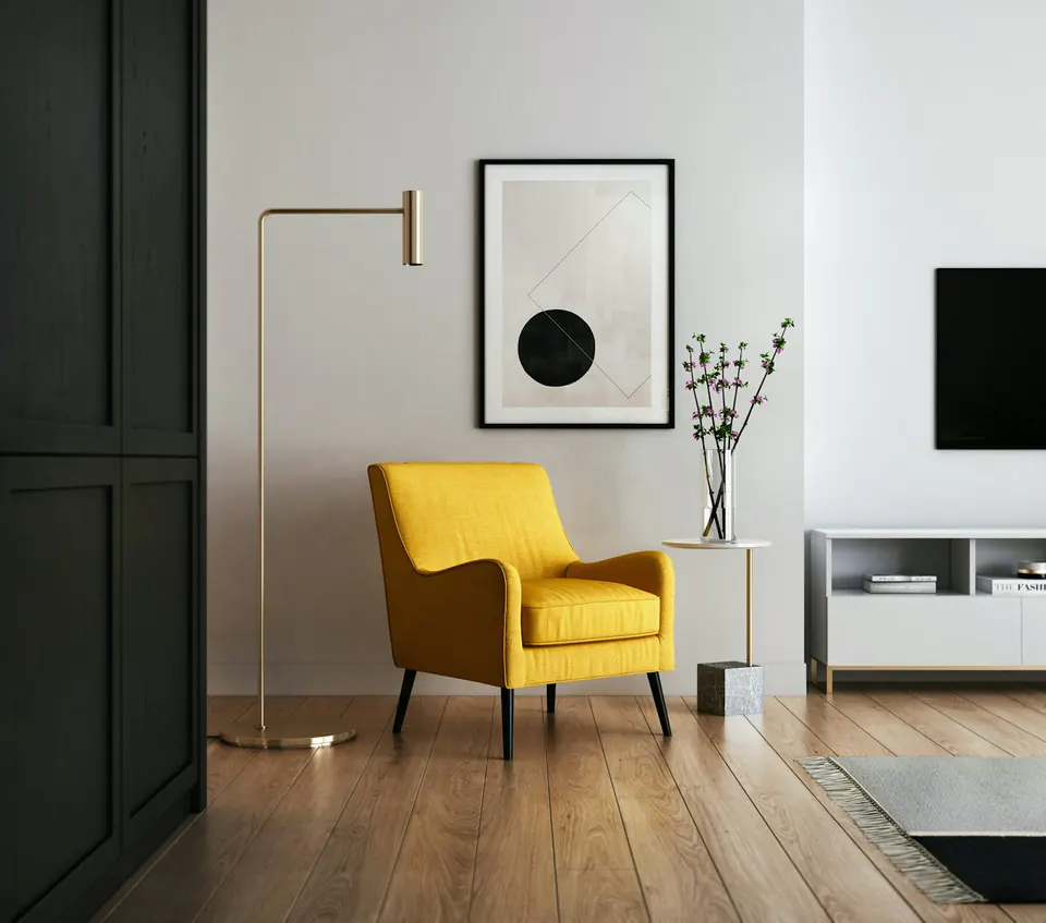 A quiet reading corner with a simple chair, timber floor, and slim brass lamp